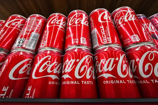 Cans of Coca-Cola are on display at a grocery market in Uniontown, Pa., April 24, 2022. The soft drink giant's sponsorship of the flagship U.N. climate conference, known as COP27, sparked an online backlash and highlighted broader concerns about corporate lobbying and influence. (AP Photo/Gene J. Puskar, File)