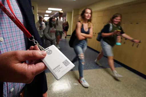Brent Kiger, Olathe Public Schools' director of safety service, displays a panic-alert button while students at Olathe South High School rush between classes Friday, Aug. 19, 2022, in Olathe, Kan. The district introduced the buttons, which allow staff to trigger a lockdown that will be announced with flashing strobe lights, a takeover of staff computers and a prerecorded intercom announcement, at the start of this school year as part of $2.1 million plan to make district schools more secure. (AP