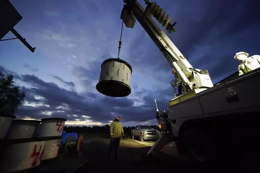 FILE- A worker stands by to guide a spool of electrical wire being loaded onto his truck before heading out at dawn, inside a tent city for electrical workers in Amelia, La., on Sept. 17, 2021. Louisiana’s largest power company is asking the Federal Emergency Management Agency for $450 million to make its electric grid more resilient, under a program to help communities prepare for hurricanes and other extreme weather. Entergy Corp.’s eight grant applications include three of the four projec
