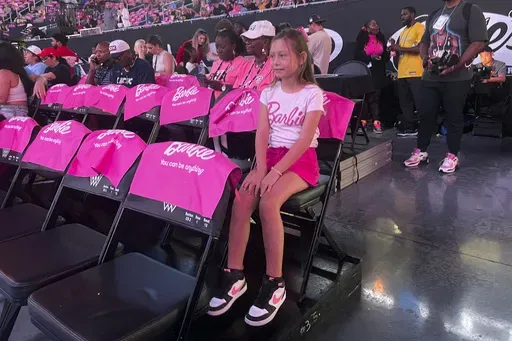 Lily Smith, 8, watches a pregame show before her first-ever WNBA basketball game Friday, Aug. 30, 2024, in Chicago. WNBA re-entered the Barbie world with Angel Reese and the Chicago Sky hosting the first-ever game themed after the doll. Lily says she likes playing with Barbies, and Barbie Night makes her feel more excited about basketball. (AP Photo/Claire Savage)