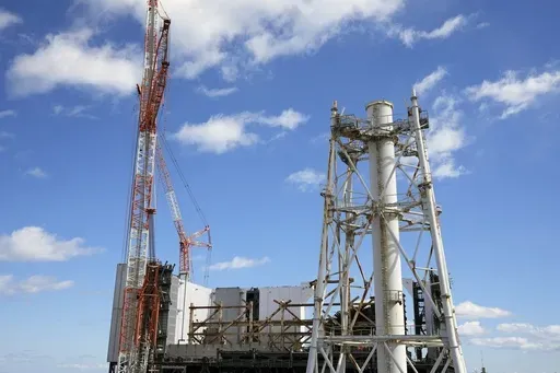 The damaged Unit 1 reactor, back, and the exhaust stack shared by the Unit 1 and 2 reactors are seen at the Fukushima Daiichi nuclear power plant, operated by Tokyo Electric Power Company Holdings (TEPCO), in Okuma town, northeastern Japan on Monday Feb. 20, 2025. (AP Photo/Eugene Hoshiko)
