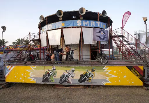 Performers prepare motorcycles in front of the "Wall of Death", also known as a motordrome or silodrome, prior the motorcycle rally in Belgrade, Serbia, Thursday, Aug. 18, 2022. Motorcycle enthusiasts in Belgrade were in for a trip down the memory lane last week when near-forgotten Well of Death stunt show came to town. (AP Photo/Darko Vojinovic)