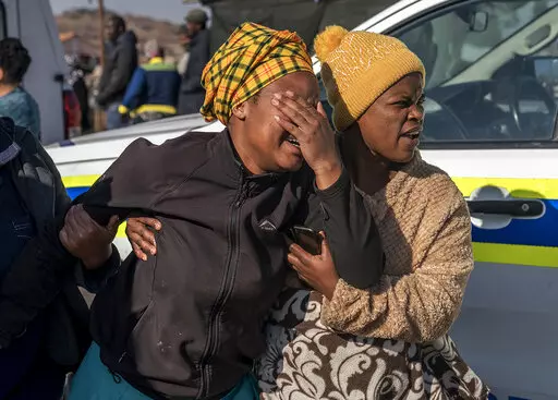 A woman weeps at the scene of an overnight bar shooting in Soweto, South Africa, Sunday July 10, 2022. A mass shooting at a tavern in Johannesburg's Soweto township has killed 15 people and left others in critical condition, according to police.  
Police say they are investigating reports that a group of men arrived in a minibus taxi and opened fire on some of the patrons at the bar shortly after midnight Sunday.  (AP Photo/Shiraaz Mohamed)