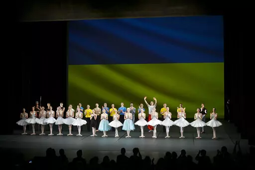 Ukrainian dancers of the Kyiv City Ballet company acknowledge applause in front of Ukrainian flag projected onto a screen at the end of a performance, at the Theatre de Chatelet, in Paris, Tuesday, March 8, 2022. The Kyiv City Ballet danced to a full house in Paris for the last show of a French tour that has left the company stranded after the war broke out in Ukraine. They described being physically and emotionally exhausted. Being given the opportunity to train and dance was for many a chance 