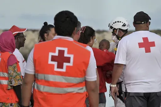 A baby is carried by members of the Red Cross in the port of La Restinga at El Hierro in the Canary Islands on Saturday, June 6, 2024, after being rescued by the Spanish Sea Rescue. Spain's Canary Islands are struggling to deal with thousands of teenagers and children traveling alone to the archipelago from Senegal, Mali, and other African nations. (Europa Press via AP)