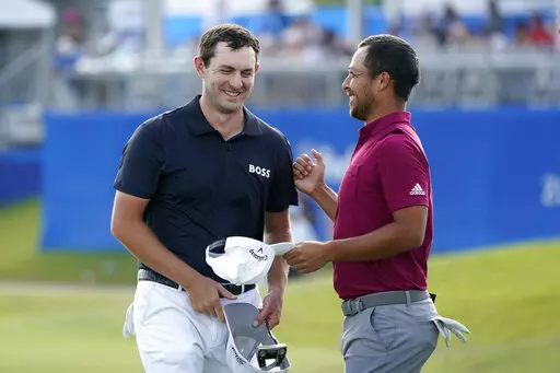 Patrick Cantlay greets teammate Xander Schauffele, right, on the 18th green after completing their third round of the PGA Zurich Classic golf tournament, Saturday, April 23, 2022, at TPC Louisiana in Avondale, La. (AP Photo/Gerald Herbert)