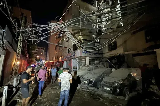 People gather near a destroyed building that was hit by an Israeli airstrike in the southern suburbs of Beirut, Lebanon, Tuesday, July 30, 2024. An Israeli airstrike hit Hezbollah's stronghold south of Beirut Tuesday evening causing damage, a Hezbollah official and the group's TV station said. (AP Photo/Hussein Malla)