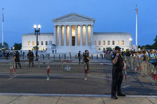 Demonstrators protest outside of the U.S. Supreme Court as law enforcement officers stand ready, May 3, 2022, in Washington. A leaked draft of a Supreme Court opinion overruling the landmark Roe v. Wade decision has thrust companies into the limelight on what’s arguably the most divisive issue in American politics. (AP Photo/Alex Brandon, File)