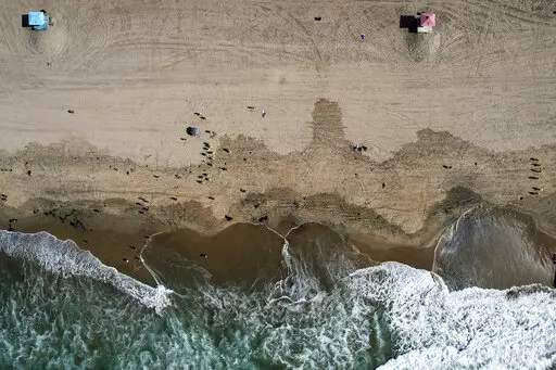 In this aerial photo taken with a drone, workers in protective suits continue to clean an oil-contaminated beach in Huntington Beach, Calif., Oct. 11, 2021. According to a federal report released Wednesday, Sept. 28, 2022, oil and natural gas spills from tanker ships and pipelines in U.S. waters dropped dramatically from the last decade of the 1990s to the one from 2010 through 2019. (AP Photo/Ringo H.W. Chiu, File)