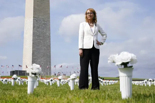 Former congresswoman and gun violence survivor Gabby Giffords stands among vases of flowers that make up the Gun Violence Memorial installation near the Washington Monument on the National Mall in Washington, Tuesday, June 7, 2022. The flowers are meant to represent the number of Americans who die from gun violence each year. (AP Photo/Patrick Semansky)