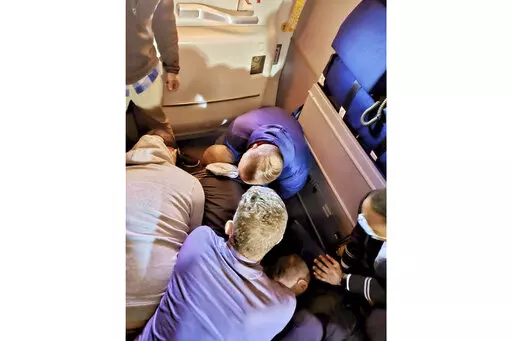 This image provided by Simik Ghookasian shows passengers and crew members restraining a man who according to federal authorities tried to open an airliner’s emergency door and tried to stab a flight attendant on a weekend flight from Los Angeles to Boston on Sunday, March 5, 2023. Simik Ghookasian, a passenger, said in a telephone interview that he was seated several rows behind the suspect, identified by federal authorities as Francisco Severo Torres, when he heard a commotion. (Simik Ghookas