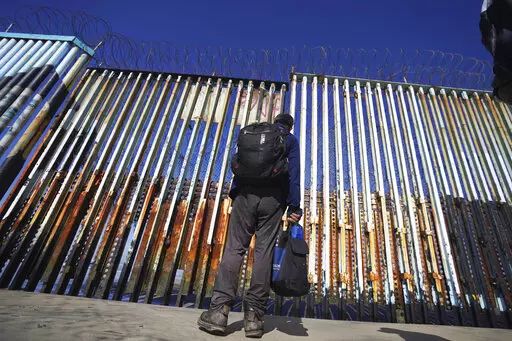 A migrant waits on the Mexican side of the border after United States Customs and Border Protection officers detained a couple of migrants crossing the US-Mexico border on the beach, in Tijuana, Mexico, Jan. 26, 2022. A federal judge in Louisiana has on Wednesday, April, 27, 2022, ordered the Biden administration to stop phasing out a public health rule that allows the expulsion of migrants without an opportunity to seek asylum. (AP Photo/Marco Ugarte, File)