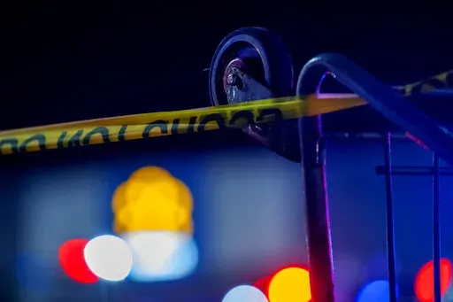 A grocery cart is used to hold caution tape as police work the scene of a shooting at the West Side Walmart in Evansville, Ind., Thursday, Jan. 19, 2023. Authorities in Indiana say a 25-year-old man opened fire in a Walmart store where he once worked, wounding at least one person before officers fatally shot him. (MaCabe Brown /Evansville Courier & Press via AP)