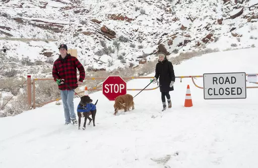 Parker Smith and Hillary Smith hike along a closed road outside Arches National Park in Utah which is closed due to the partial government shutdown, in January 2019. Arizona's Grand Canyon National Park and all five national parks in Utah will remain open if the U.S. government shuts down, Sunday, Oct. 1, 2023. Arizona Gov. Katie Hobbs and Utah Gov. Spencer Cox say that the parks are important destinations and local communities depend on dollars from visitors. (Rick Egan/The Salt Lake Tribune vi