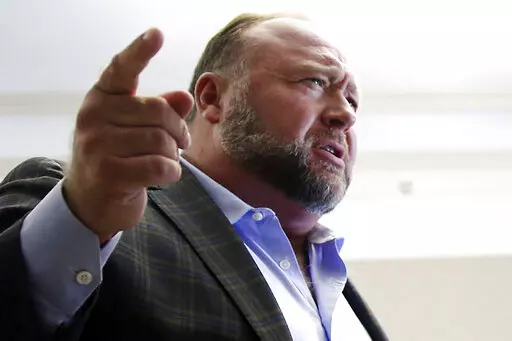 Alex Jones talks to media during a midday break in his trial at the Travis County Courthouse in Austin, Texas, on July 26, 2022. A six-member jury with several alternates in Connecticut will begin hearing evidence, Tuesday, Sept. 13, 2022, on how much Jones should pay the families, since he already has been found liable for damages to them. The trial is expected to last about four weeks. (Briana Sanchez/Austin American-Statesman via AP, Pool)