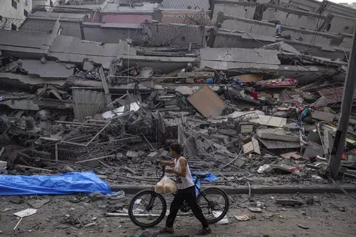 A Palestinian child walks with a bicycle by the rubble of a building after it was hit by an Israeli airstrike, in Gaza City, Sunday, Oct. 8, 2023. A new U.N. report paints a stark picture of the devastating collapsing Palestinian economy after a month of war and Israel’s near total siege of Gaza. (AP Photo/Fatima Shbair, File)