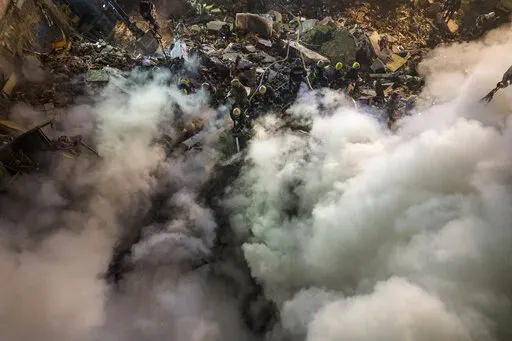Emergency workers clear the rubble after a Russian rocket hit a multistory building leaving many people under debris in the southeastern city of Dnipro, Ukraine, Saturday, Jan. 14, 2023. (AP Photo/Evgeniy Maloletka)