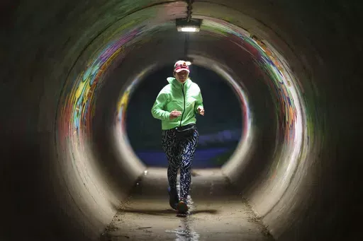 Ultra runner Helen Ryvar runs through an underpass in Wrexham during running a half marathon in Wrexham, Wales, Wednesday, March 20, 2024. Helen who took up running in 2020 just before lockdown completes her daily half marathon early so as to fit in a full time job and being a single parent to 3 children. (AP Photo/Jon Super)