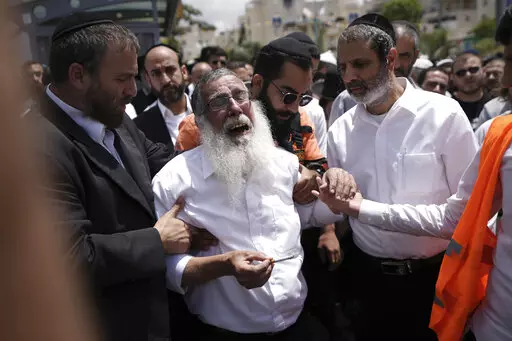 Ultra-Orthodox Jewish mourners encircle a man overcome with grief at the funeral for Yonatan Havakuk and Boaz Gol, a day after they were killed in a stabbing attack in Elad, Israel, Friday, May 6, 2022. Israeli security forces waged a massive manhunt Friday for two Palestinians suspected of carrying out the stabbing attack on Thursday near Tel Aviv that left three Israelis dead. (AP Photo/Ariel Schalit)