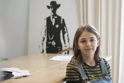 Ola Kozak, 11, sits at the table where she used to do her homework at the family home in Warsaw, Poland, Friday April 5, 2024. Ola is happy that Poland's government has ordered strict limits on the amount of homework that teachers can impose on the lower grades, starting in April. Julian enjoyed doing his homework. (AP Photo/Czarek Sokolowski)