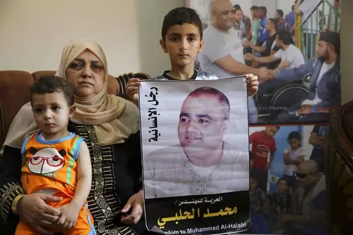 Amal el-Halabi holds her grandson Fares while her grandson Amro, 7, holds a picture of his father Mohammed el-Halabi, Gaza director of the international charity World Vision, who is detained and accused by Israeli security of diverting sums to Hamas that exceed its total budget, at his family house in Gaza City, Aug. 8, 2016. In May 2022, nearly six years after Israel accused Mohammed el-Halabi of diverting tens of millions of dollars from an international charity to Gaza's militant Hamas rulers