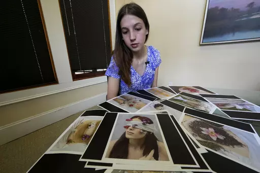 Gabrielle Jameson, a victim of a sexual assault, looks over photographs from her college thesis project, which she describes as part of her healing process, at the office of her attorney Tony Le Mon, in Covington, La., Tuesday, June 6, 2023. Jameson, who watched the man who coerced her into a sex act when she was 16 walk free in a plea deal, lost a legal battle, Tuesday, June 27, to sue the prosecutor in the case. (AP Photo/Gerald Herbert, File)