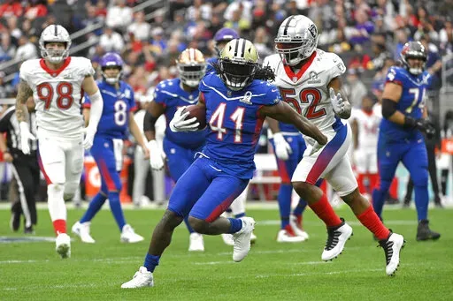 NFC running back Alvin Kamara of the New Orleans Saints (41) rushes as AFC inside linebacker Denzel Perryman of the Las Vegas Raiders (52) closes in during the first half of the Pro Bowl NFL football game, Sunday, Feb. 6, 2022, in Las Vegas. (AP Photo/David Becker)