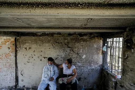 Camila Lange, who is 7-months-pregnant, and her husband Felipe Corvalan sit with their dog Florencia inside their home that was burned by a deadly wildfire in Vina del Mar, Chile, Monday, Feb. 5, 2024. (AP Photo/Esteban Felix)