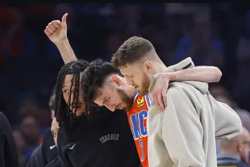 Oklahoma City Thunder forward Chet Holmgren, center, gives a thumbs-up as he is helped off the court by Thunder forward Jaylin Williams, left, and center Isaiah Hartenstein, right, during the first half of an NBA basketball game against the Golden State Warriors, Sunday, Nov. 10, 2024, in Oklahoma City. (AP Photo/Nate Billings)