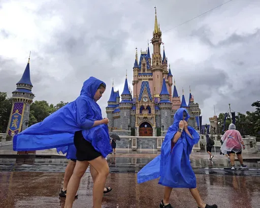 Guests at the Magic Kingdom at Walt Disney World brave wind and rain as bands of weather from Hurricane Debby pass through Central Florida, Monday, Aug. 5, 2024, in Bay Lake, Fla. (Joe Burbank/Orlando Sentinel via AP)