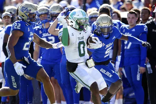 Tulane's Shaadie Clayton-Johnson completes a long gain while being forced out of bounds by Tulsa defenders LJ Wallace, left, and Kenney Solomon during an NCAA college football game in Tulsa, Okla. on Saturday, Nov. 5, 2022. (AP Photo/Dave Crenshaw)