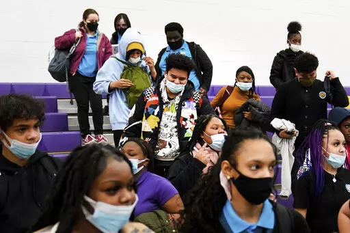 Students wearing mask as a precaution against the spread of the coronavirus line up to receive KN95 protective masks at Camden High School in Camden, N.J., Feb. 9, 2022. U.S. COVID-19 cases are up, leading a smattering of school districts, particularly in the Northeast, to bring back mask mandates and recommendations for the first time since the omicron winter surge ended and as the country approaches 1 million deaths in the pandemic. (AP Photo/Matt Rourke, File)
