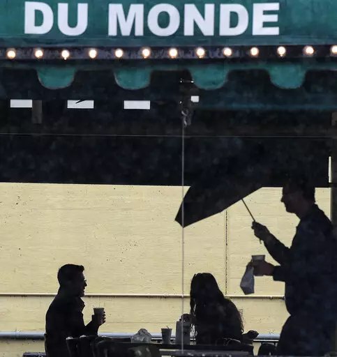 People enjoy a beignet and a hot café au lait at Cafe du Monde on a rainy day, Tuesday, March 2, 2021, in New Orleans. Bars, restaurants and other businesses in New Orleans are no longer required to make patrons show proof of vaccination against COVID-19 or a negative test for the disease, the city said Monday, March 21, 2022, in a news release. (Max Becherer/The Times-Picayune/The New Orleans Advocate via AP, File)