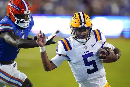 LSU quarterback Jayden Daniels (5) slips by Florida linebacker Brenton Cox Jr. for a 9-yard touchdown run during the second half of an NCAA college football game, Saturday, Oct. 15, 2022, in Gainesville, Fla. (AP Photo/John Raoux)