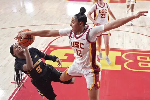 Michigan guard Brooke Daniels, left, has her shot blocked by Southern California guard JuJu Watkins during the second half of an NCAA college basketball game, Sunday, Dec. 29, 2024, in Los Angeles. (AP Photo/Mark J. Terrill)