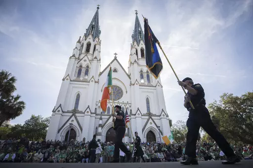 Participants carry flags past the Cathedral Basilica of St. John the Baptist while marching in the St. Patrick's Day parade, March 17, 2023, in historic downtown Savannah, Ga. Savannah, Georgia's oldest city, is planning a supersized celebration as it marks the 200th anniversary of its beloved St. Patrick's Day parade. City Manager Jay Melder says he's expecting historic crowds for the Irish-themed parade Saturday, March 16, 2024. (AP Photo/Stephen B. Morton)