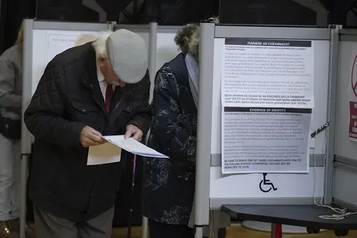 A man looks at the ballot papers before casting his vote in the local and European elections at the Deaf Village in Dublin, Ireland, Friday June 7, 2024. (Niall Carson/PA via AP)