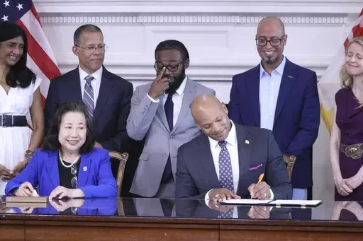Maryland Gov. Wes Moore signs an executive order to issue more than 175,000 pardons for marijuana convictions on Monday, June 17, 2024 in Annapolis, Md. Maryland Secretary of State Susan Lee is seated left. Standing left to right are Lt. Gov. Aruna Miller, Maryland Attorney General Anthony Brown, Shiloh Jordan, Jason Ortiz, director of strategic initiatives for Last Prisoner Project and Heather Warnken, executive director of the University of Baltimore School of Law Center for Criminal Justice. 