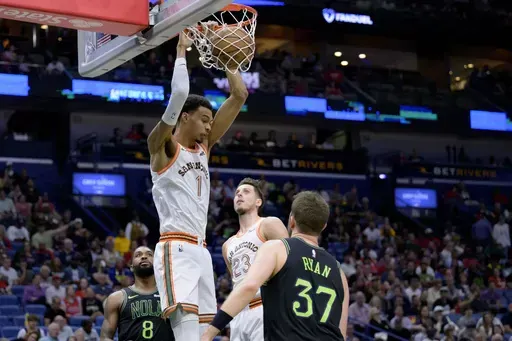 San Antonio Spurs center Victor Wembanyama (1) dunks next to New Orleans Pelicans forward Matt Ryan (37) during the first half of an NBA basketball game in New Orleans, Friday, April 5, 2024. (AP Photo/Matthew Hinton)