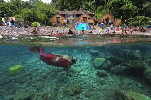 Queen Pangke Tabora swims in her mermaid suit as she conducts a mermaiding class in front of the Ocean Camp in Mabini, Batangas province, Philippines on Sunday, May 22, 2022. For the transgender Filipina woman approaching middle age, seeing her legs encased in vibrant, scaly-looking neoprene three years ago was the realization of a childhood dream. (AP Photo/Aaron Favila)