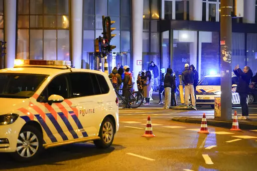 Police vehicles cordon off a wide area in Amsterdam, Netherlands, Tuesday, Feb. 22, 2022, where an armed person is holed up in the Amsterdam Apple Store with at least one hostage in an hours-long standoff with scores of police massed outside. (AP Photo/Peter Dejong)