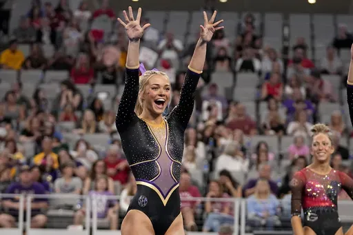 LSU's Olivia Dunne waves to fans cheering for the team as competitors warm up for the floor exercise during the NCAA women's gymnastics championships in Fort Worth, Texas, Thursday, April 18, 2024. Dunne will return for a fifth season at LSU, saying on social media she’s “not Dunne yet.” (AP Photo/Tony Gutierrez, File)