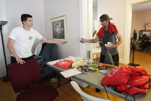 Manuel Luna, left, a volunteer at the Salvation Army, gives out items to a patron at a cooling station on July 19, 2023, in Phoenix. (AP Photo/Ross D. Franklin, File)