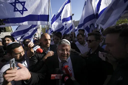 Israeli lawmaker Itamar Ben-Gvir, center, surrounded by right wing activists with Israeli flags, speaks to the media as they gather for a march in Jerusalem, Wednesday, April 20, 2022. Ben-Gvir, an ultranationalist lawmaker who was once relegated to the margins of Israeli politics, is surging in the polls ahead of November’s parliamentary elections. (AP Photo/Ariel Schalit, File)
