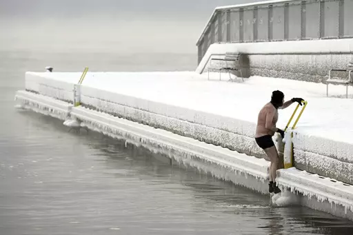 A man climbs out from the icy sea to the pier, in southern Helsinki, Finland, Tuesday, Jan. 2, 2024. Finland and Sweden have recorded this winter’s cold records on Tuesday as a temperatures plummeted to over minus 40 degrees as a result of a cold spell prevailing in the Nordic region. (Vesa Moilanen/Lehtikuva via AP)