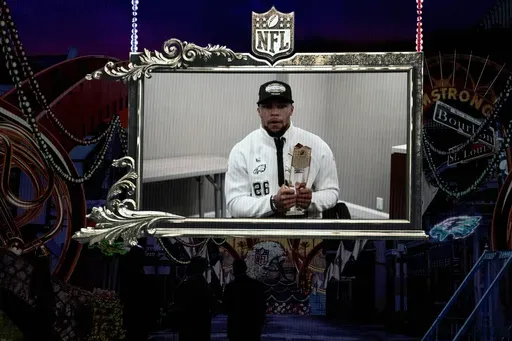 Philadelphia Eagles' Saquon Barkley, accepts the AP Offensive player of the year award on a screen during the NFL Honors award show ahead of the Super Bowl 59 football game, Thursday, Feb. 6, 2025, in New Orleans. (AP Photo/David J. Phillip)