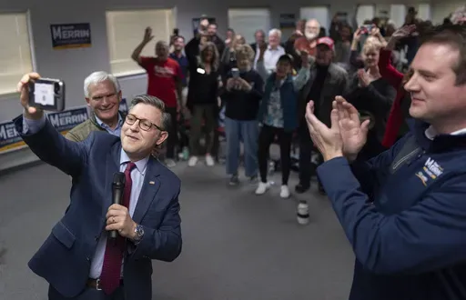 Speaker of the House Mike Johnson, R-La., second from left, joined by Rep. Bob Latta, R-Ohio, left, and Ohio state Rep. Derek Merrin, right, takes a selfie to send to Republican presidential nominee former President Donald Trump as he speaks during a campaign event at the Lucas County Republican Party headquarters in Holland, Ohio, Saturday, Oct. 26, 2024. (AP Photo/Carolyn Kaster)