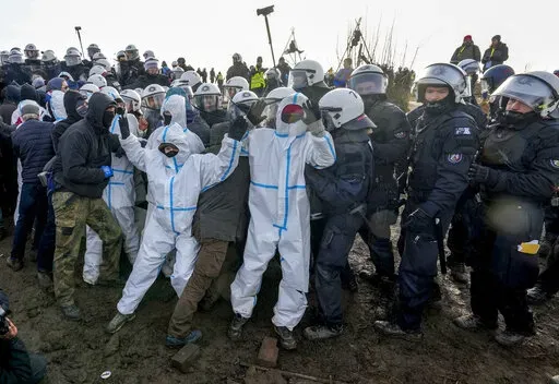Protesters clash with police officers next to the Garzweiler lignite opencast mine at the Luetzerath village near Erkelenz, Germany, Tuesday, Jan. 10, 2023. Environmental activists were locked in a standoff with police this week around the hamlet of Luetzerath that's due to be bulldozed for the expansion of a nearby lignite mine. (AP Photo/Michael Probst)