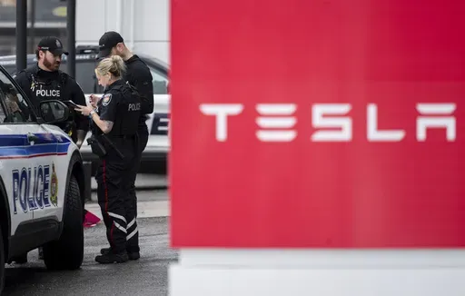Officers from Ottawa Police Service (OPS) are seen at a Tesla Service and Showroom centre after it was damaged with pink spray paint in Ottawa, on Monday, March 31, 2025. (Spencer Colby/The Canadian Press via AP)
