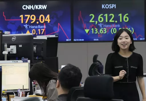 A currency trader passes by a screen showing the Korea Composite Stock Price Index (KOSPI), top right, at the foreign exchange dealing room of the KEB Hana Bank headquarters in Seoul, South Korea, Monday, June 19, 2023. Asian stock markets followed Wall Street lower Monday after the top U.S. and Chinese diplomats agreed to cooperate during a meeting held at a time of friction over an array of conflicts. (AP Photo/Ahn Young-joon)